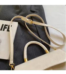 Détail du sac vintage crème, texture craquelée et dorures, posé sur une veste grise