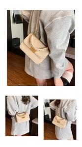 Detail of cream leather handbag featuring a chunky woven handle and gold metal buckle