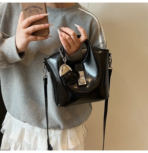 Detail der schwarzen Lackleder-Beuteltasche mit Metallschloss und Herzanhänger