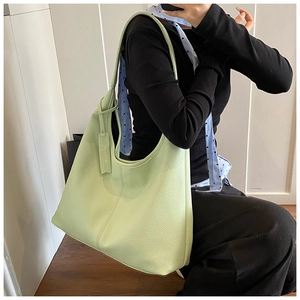 Detailed view of light green hobo bag with litchi texture on model's shoulder