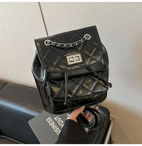 Detail of black quilted leather backpack featuring silver twist lock and chain strap