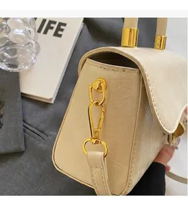 Détail de la texture en cuir plissé blanc crème et ferrures dorées du sac à main