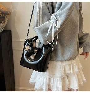 Close-up of black patent leather bucket bag with silver heart charm and metal clasp