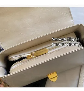 Détail de la fermeture éclair dorée lisse et du cuir crème de la pochette vintage