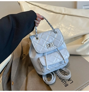 Detail of light blue quilted mini backpack featuring silver twist lock and chain handle