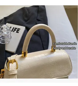Détails d'un sac à main en cuir crème avec boucles dorées et poignée ronde