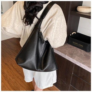 Close-up of black lychee grain leather hobo bag with a stylish hanging letter charm tag