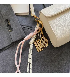 Détail d'un porte-clés en corde tressée avec pendentifs boulier et raquette dorés