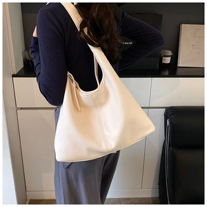 Side view of a beige pebble leather tote bag worn on shoulder for a chic commute