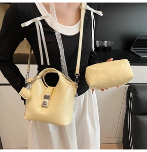 Primer plano del bolso tipo cubo de cuero amarillo crema con elegante hebilla de metal