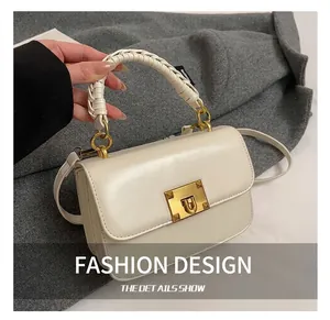Détail du sac à main crème avec poignée tressée et fermoir métallique doré à clous