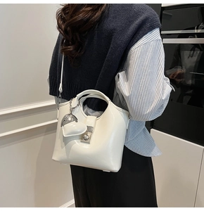 Detailansicht einer weißen halbrunden PU-Handtasche mit Herzanhänger und Metallschnalle