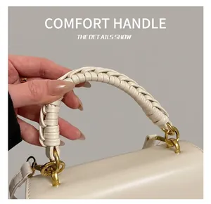 Détail de la poignée tressée et des ferrures dorées sur un sac à main rétro crème