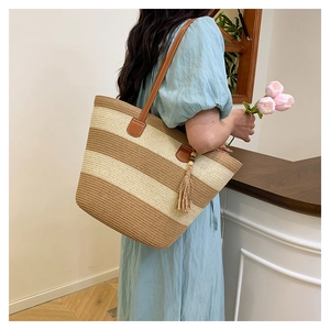 Détail du sac cabas en paille avec bandoulières en cuir marron et gland beige