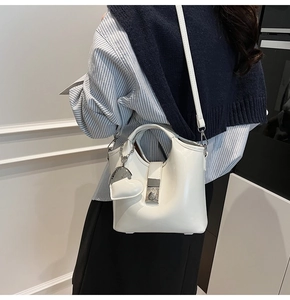 White glossy shoulder bag with heart charm and metal lock shown on a model