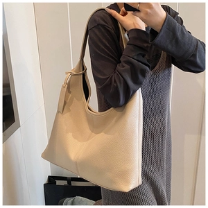 Detail of cream leather hobo bag showing litchi texture and minimalist shoulder strap