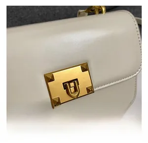 Détail du fermoir tournant en métal doré avec rivets pyramides sur un sac à main beige