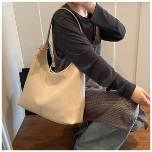 Close-up of beige lychee texture hobo bag with matching leather charm on model