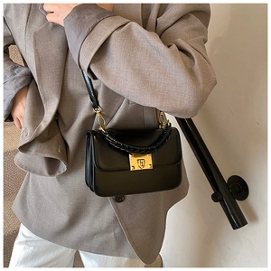 Détail du sac à bandoulière en cuir noir avec poignée tressée et boucle dorée carrée