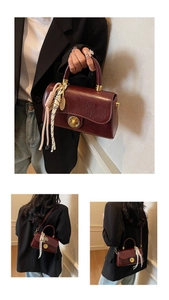 Détail d'un sac à main rouge foncé brillant avec plis vintage et fermoir doré