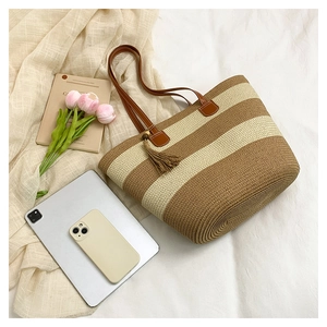 Détail du sac cabas tissé à rayures avec poignées en cuir marron et pompon décoratif