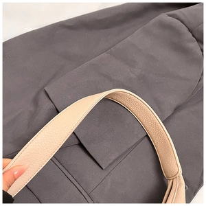 Detail of beige lychee textured leather strap with precise stitching on a shoulder bag