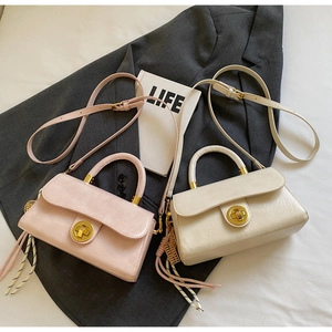 Détail de mini sacs en cuir texturé rose et blanc avec fermoirs dorés et charms