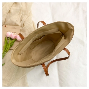 Détail intérieur du sac cabas en paille avec poche zippée et doublure en tissu clair