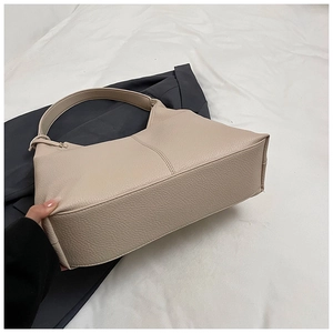 Detail view of the beige lychee texture leather stitching on the hobo bucket bag