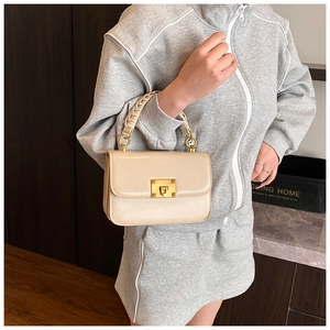 Detail of light beige leather handbag featuring a braided handle and gold clasp hardware