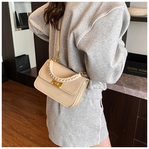Detail of beige glossy PU handbag showing gold square lock and woven handle with strap