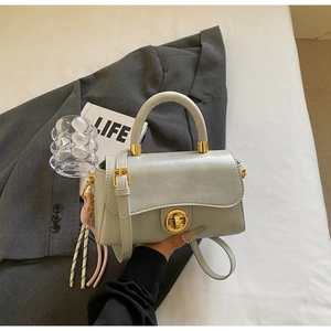 Détail du sac carré vintage avec fermoir doré tournant et breloque à pompon colorée