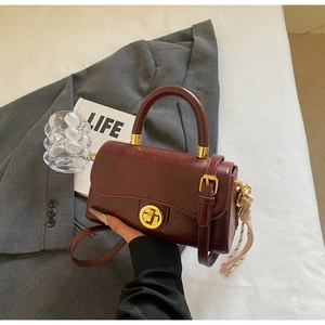 Vue détaillée du sac en cuir plissé bordeaux avec fermoir doré et pampille décorative