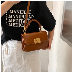 Close-up of caramel leather handbag with woven handle detail and gold twist lock