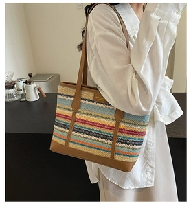 Close-up of rainbow straw woven tote bag with brown leather handles and side details