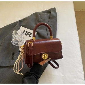 Détail du sac en cuir bordeaux avec fermoir doré et cordelette décorative beige