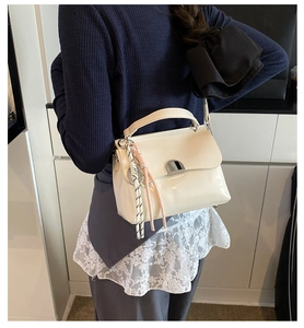 Detail of cream leather handbag with silver metallic lock and woven rope pendant strap