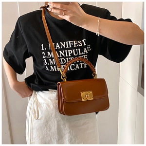 Détail d'un sac bandoulière en cuir marron avec fermoir doré et poignée tressée sur modèle
