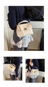 Detail of cream white faux leather handbag with silver clasp and woven charm detail