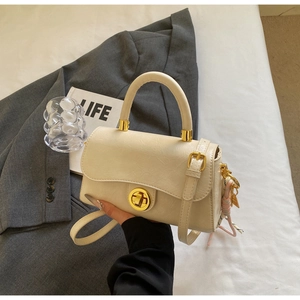 Détail du sac à rabat crème avec fermoir doré, fini texturé et accent de foulard