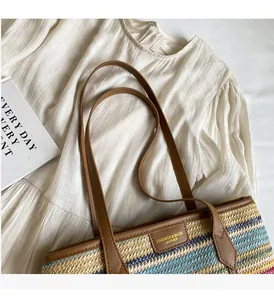 Detail of colorful woven straw tote bag with brown leather handles and gold metal logo plate