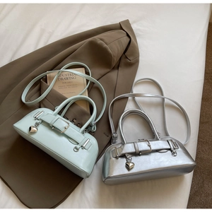 Détail de mini sacs Boston avec boucles décoratives et breloques cœur en vert et argent