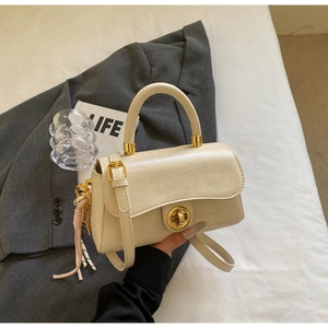 Détail du sac rétro blanc cassé avec fermoir doré rotatif et charme en foulard de soie