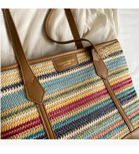 Close-up of colorful striped woven tote with brown leather trim and fashion logo detail