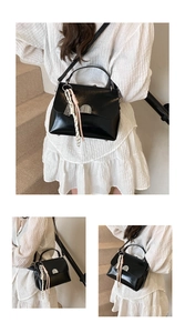 Detail of a black patent leather handbag with silver clasp and colorful tassel charm