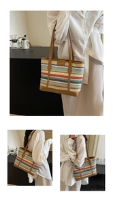 Close-up of colorful striped woven tote bag with brown leather handles and brand logo