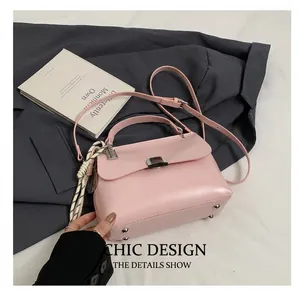 Detail of pink faux leather handbag with silver twist lock and woven rope charm