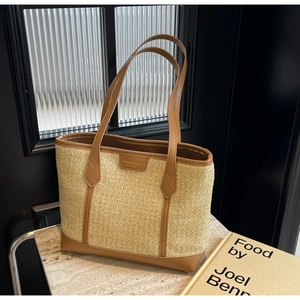 Detail of cream woven tote bag with brown leather handles on marble surface