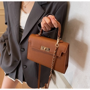 Detailed view of brown lychee-grain handbag with metallic twist lock and crossbody strap