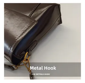 Détail du crochet en métal doré sur le sac à bandoulière en cuir marron foncé
